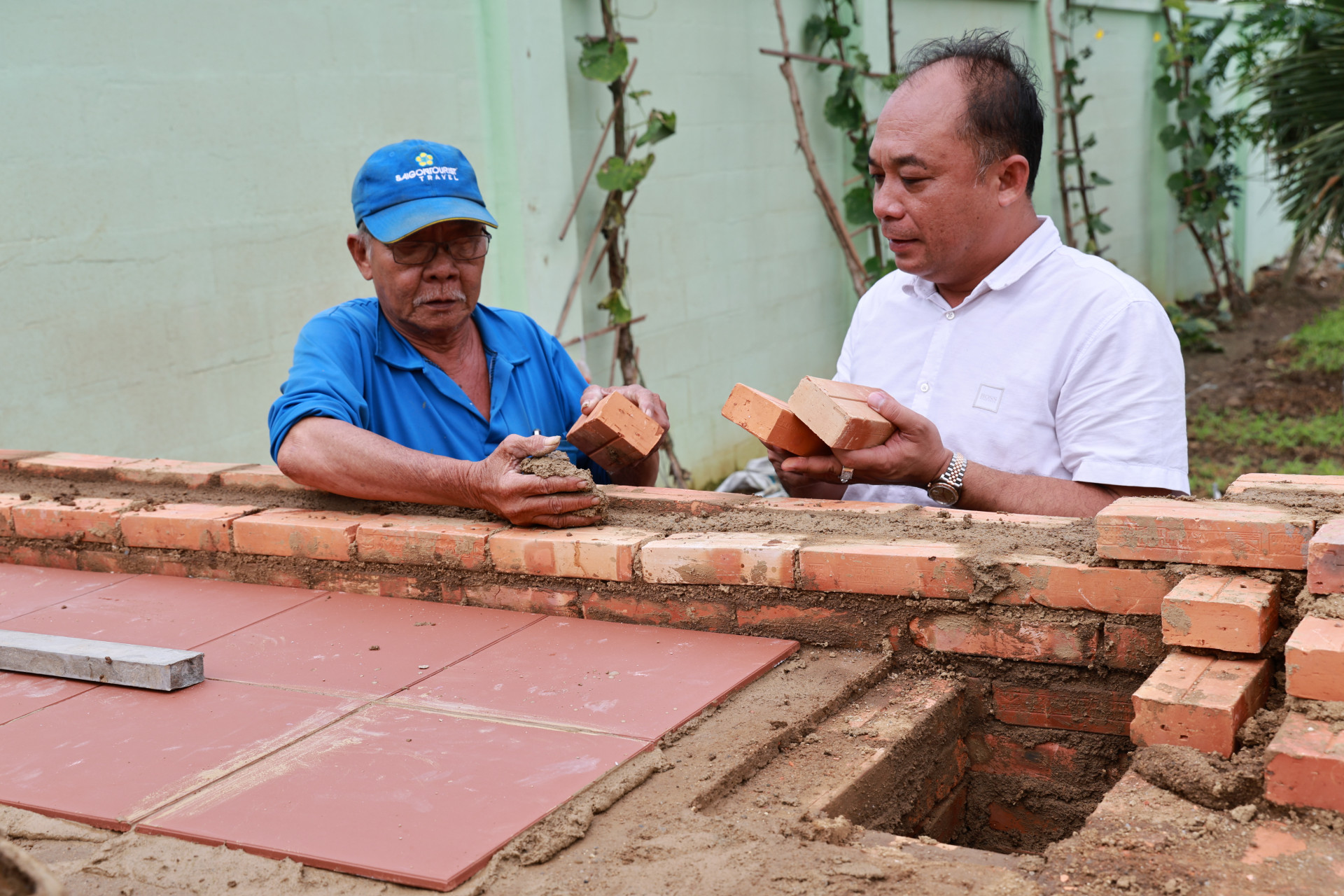 Ông Nguyễn Quang Duy (bên phải) học xây lò bánh mì.
