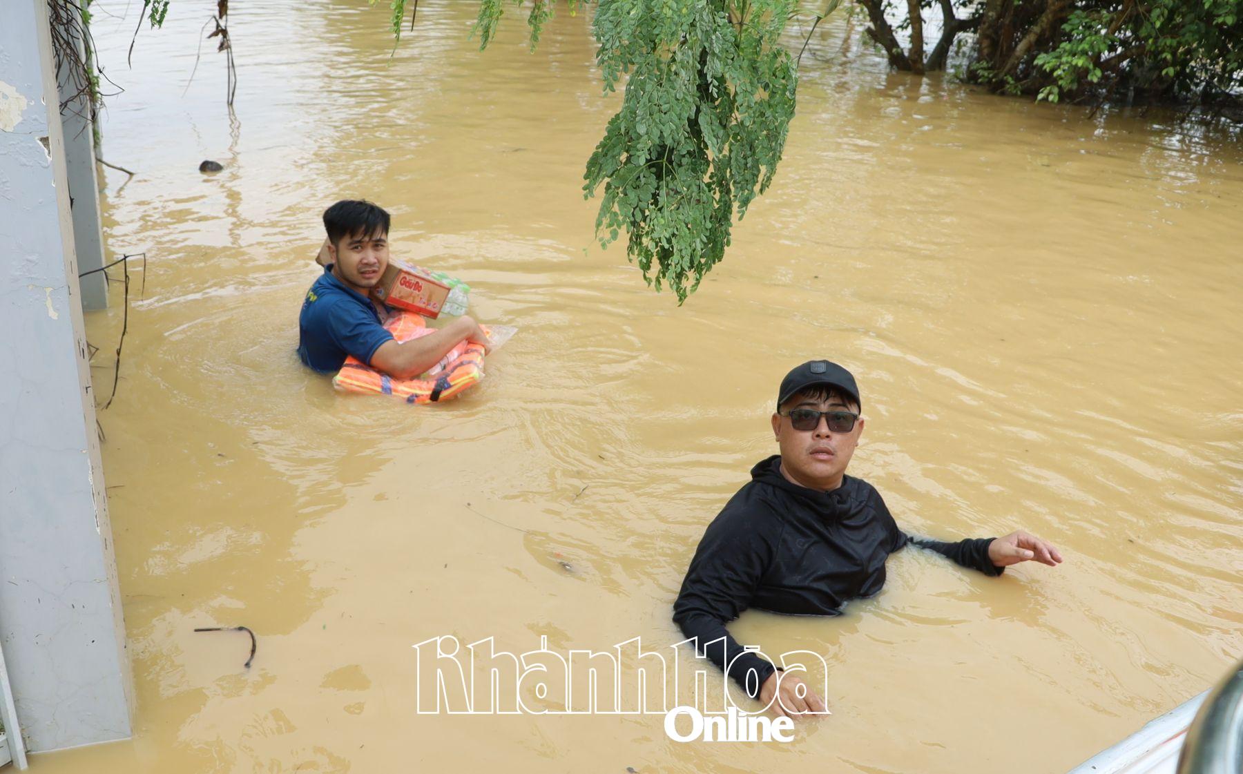 Các tình nguyện viên, lực lượng công an đầm mình trong nước lũ đưa hàng cứu trợ cho người dân.