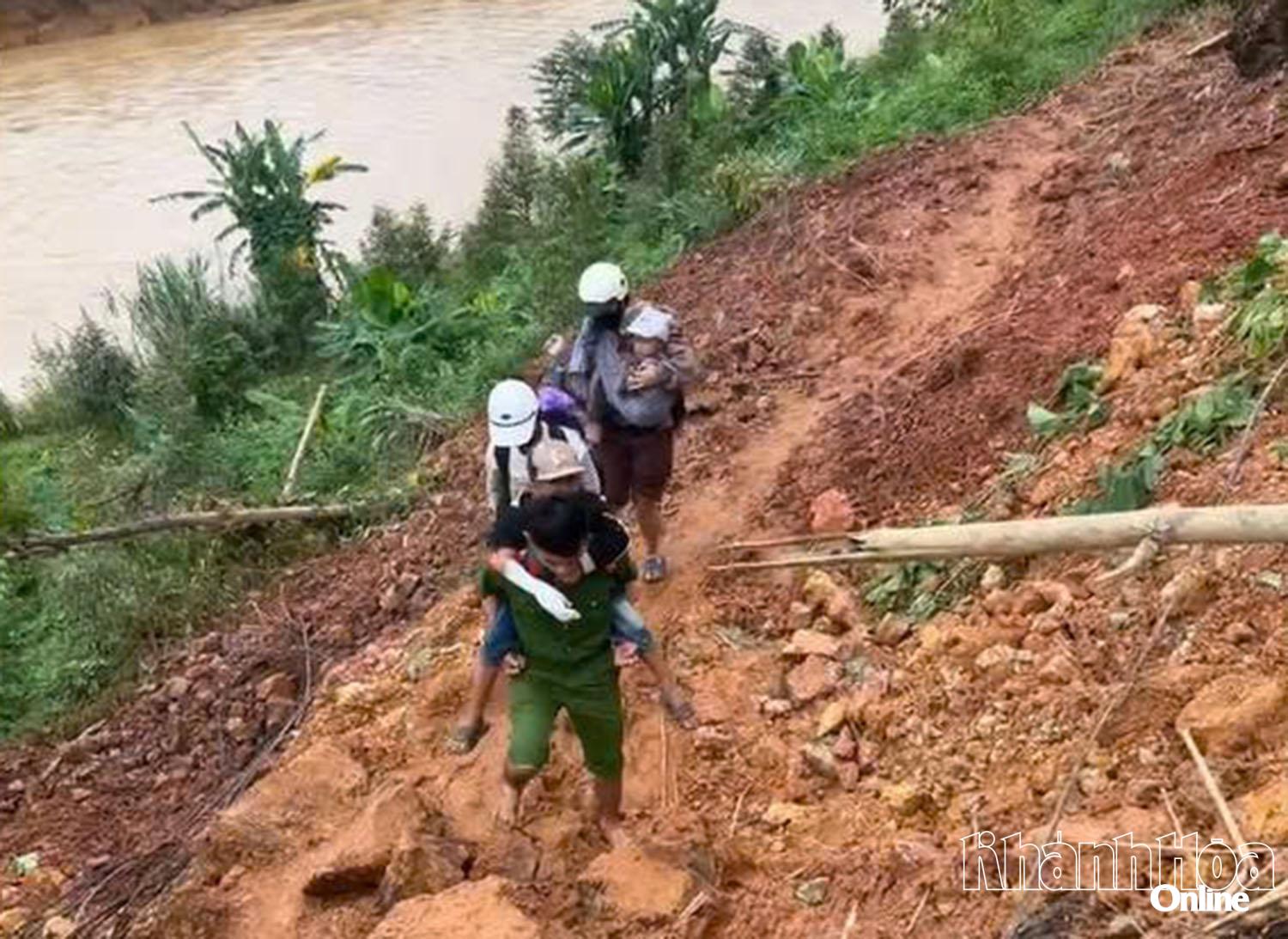 Cán bộ Công an xã Tấy Khánh Sơn cõng bà Cao Thị Cần khẩn trương di dời đến nơi an toàn