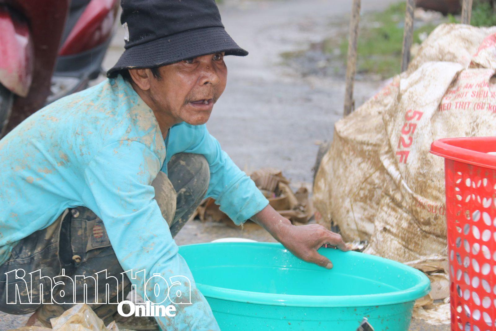 Một người dân cố gắng rửa bát, đĩa trong một chậu nước đục ngầu