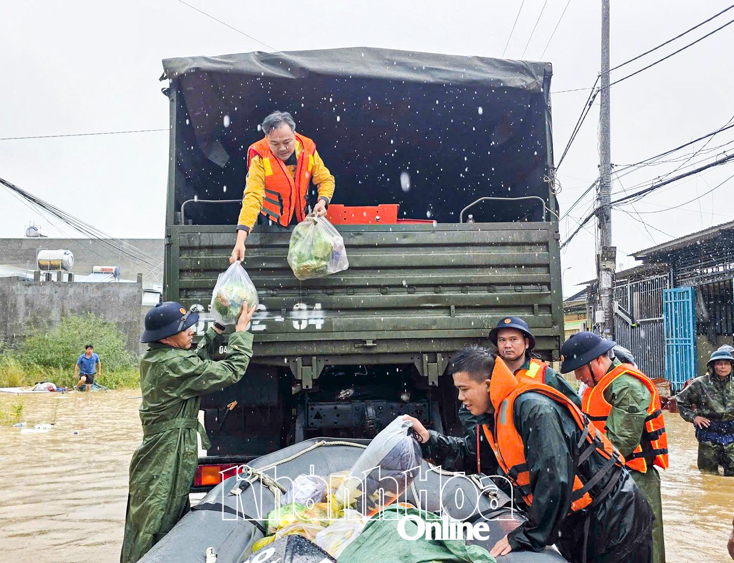 Chuyển thực phẩm từ xe xuống thuyền chuyển tải đưa vào vùng lũ.