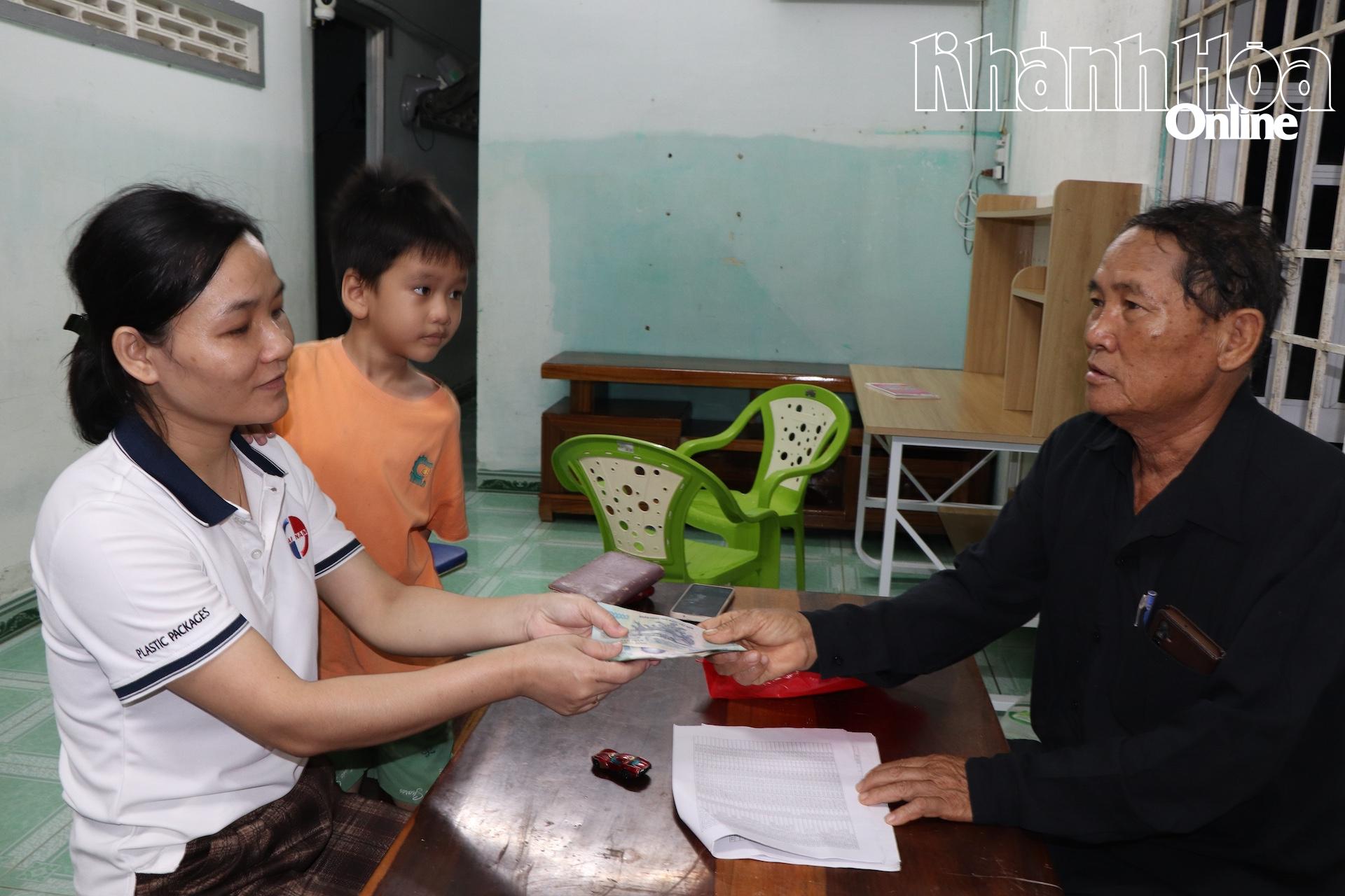 Trưởng thôn Trung 1 chi trả tiền hỗ trợ tại nhà một người dân.