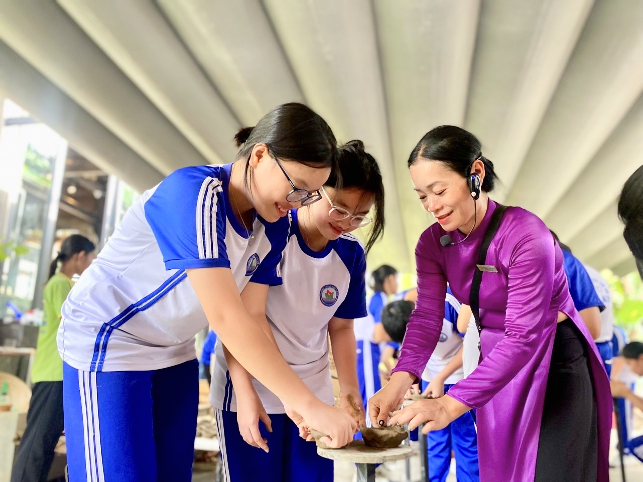 Nhân viên Khu Làng nghề truyền thống ở Khu du lịch Champa Island hướng dẫn học sinh tự tay làm gốm.