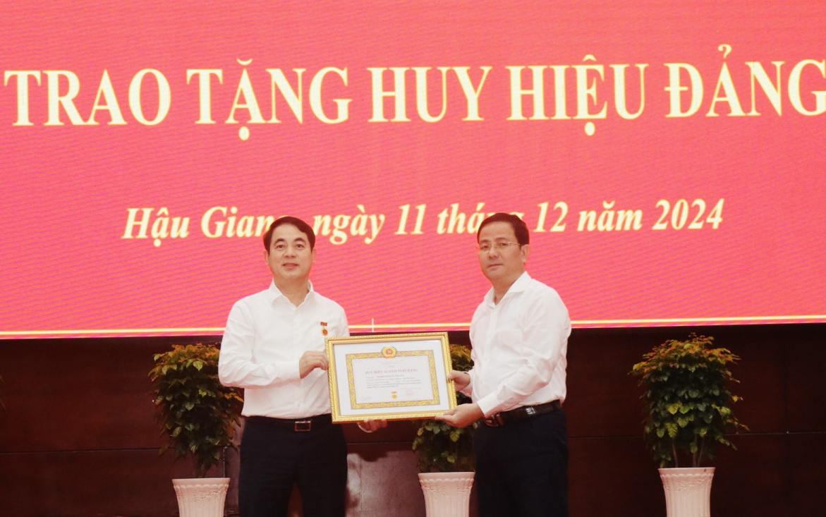 Phó Bí thư Thường trực Tỉnh ủy Hậu Giang Trần Văn Huyến trao Huy hiệu 30 năm tuổi Đảng cho Bí thư Tỉnh ủy Khánh Hòa Nghiêm Xuân Thành.