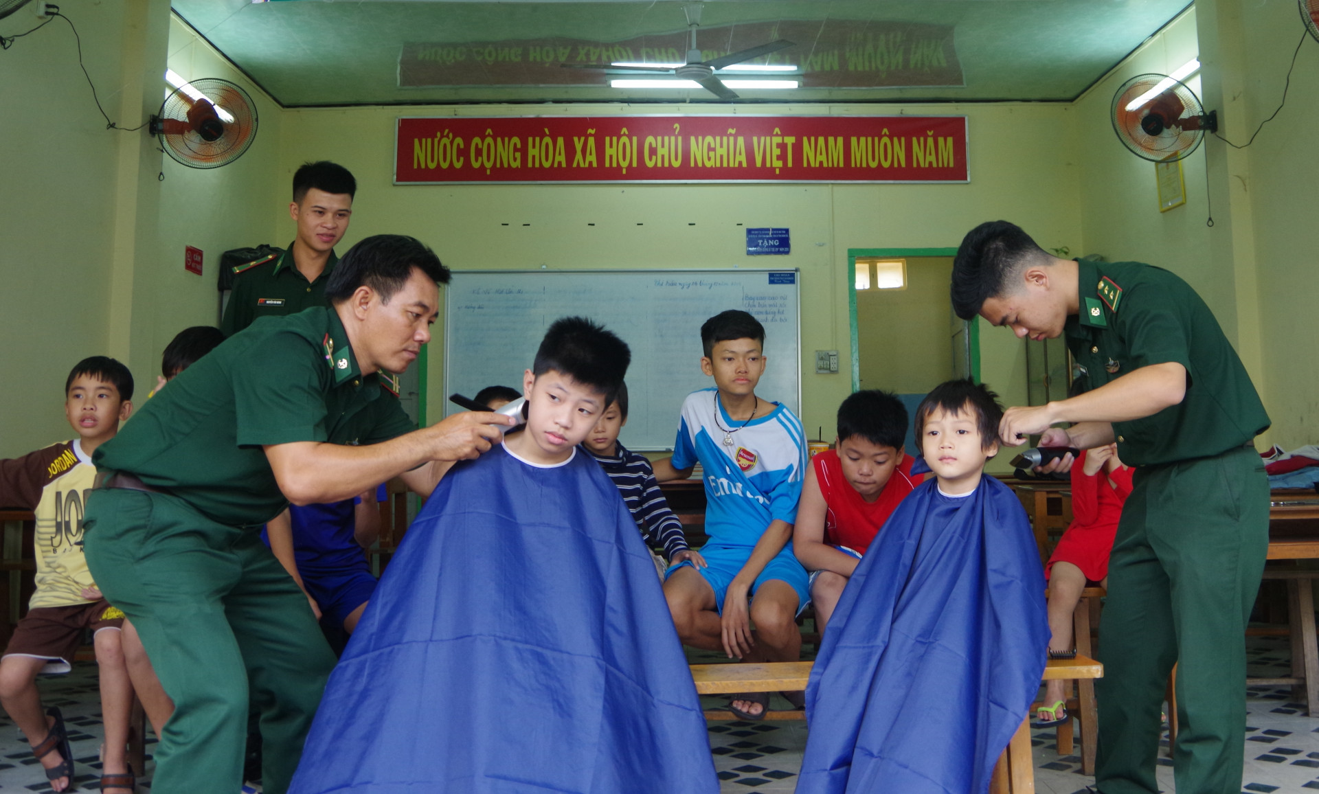 Cán bộ, đoàn viên thanh niên Bộ đội Biên phòng tỉnh cắt tóc cho trẻ em.