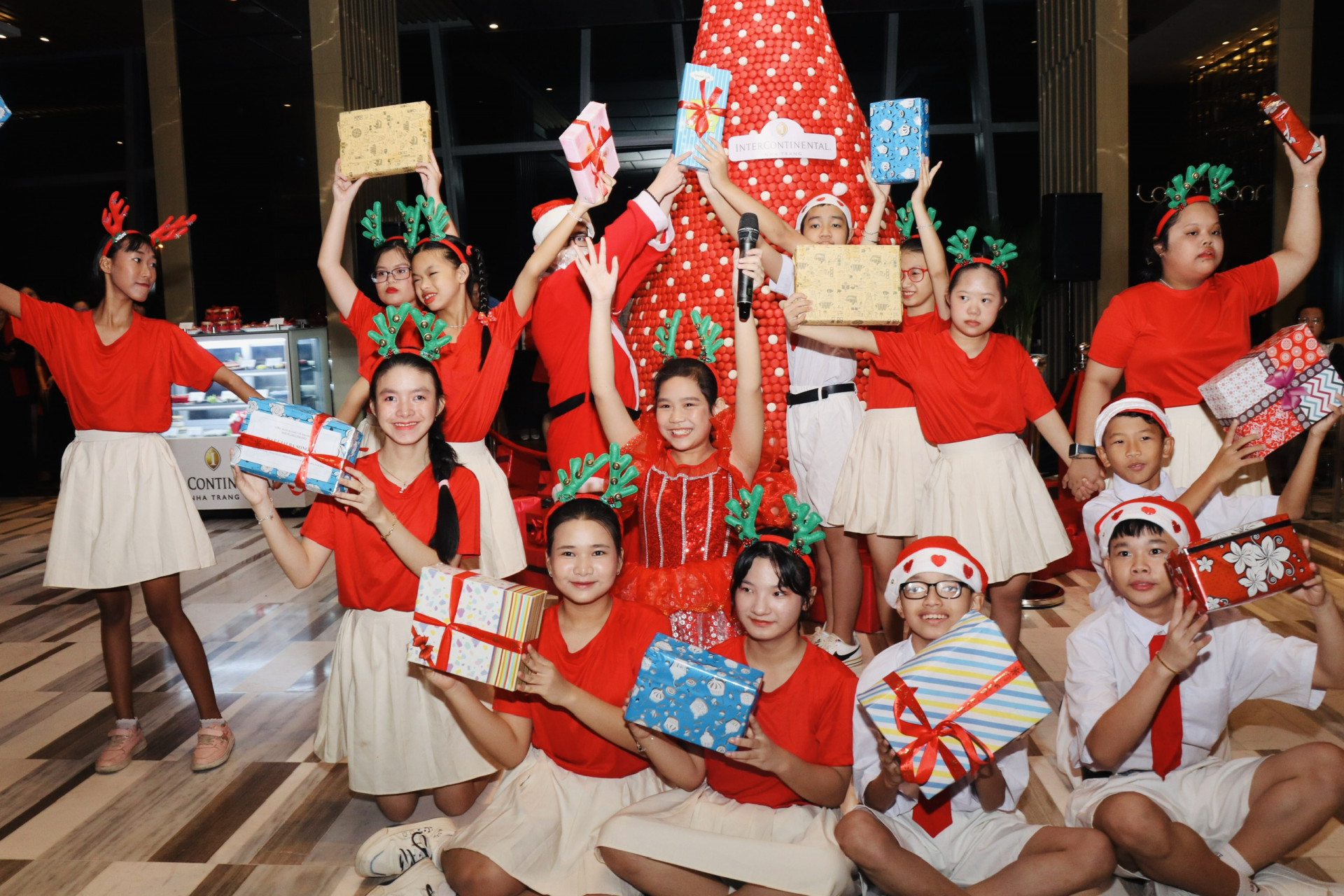 Children sing Christmas carols next to the Macaron Christmas tree at the InterContinental