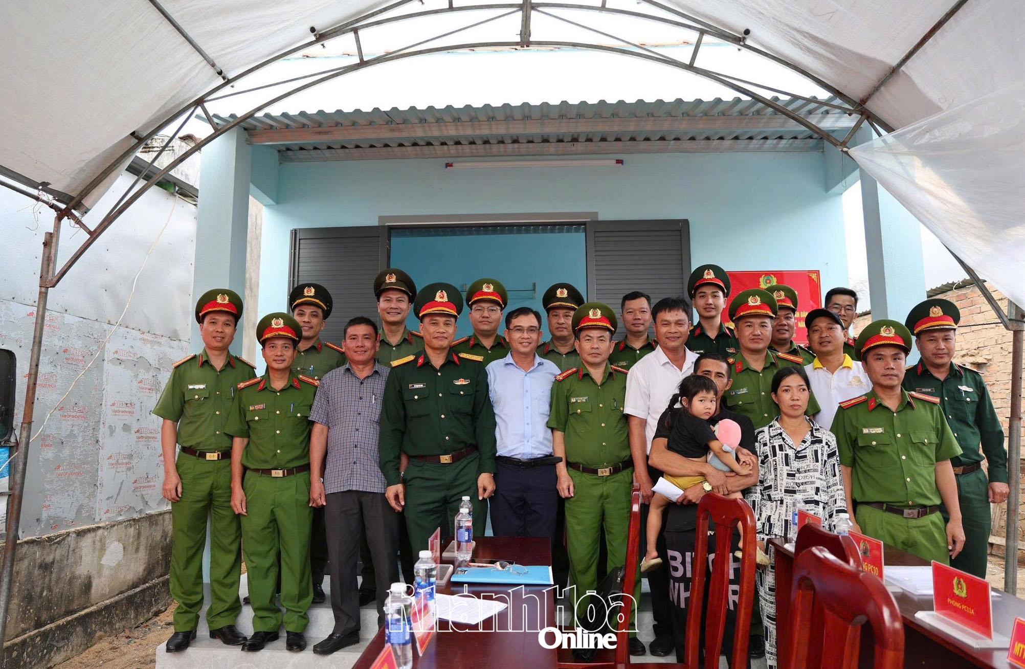 Lực lượng chức năng và chính quyền địa phương cùng gia đình ông Trần Nam chụp ảnh lưu niệm trong ngày khánh thành căn nhà mới.