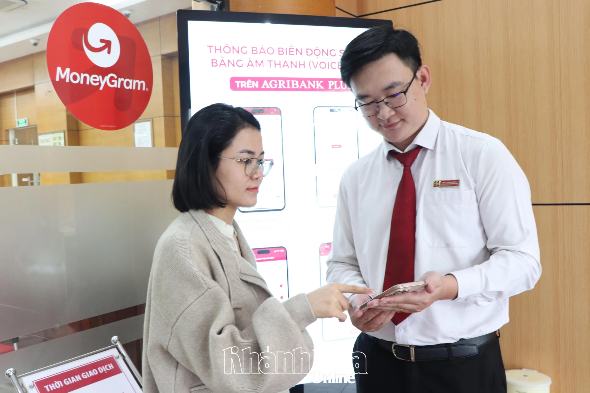 Nhân viên một chi nhánh ngân hàng hướng dẫn khách hàng sử dụng ứng dụng ngân hàng số.