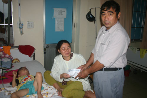 Đại diện lãnh đạo xã Phước Đồng trao tiền hỗ trợ từ Báo Sài Gòn Giải Phóng cho gia đình chị Hồng.