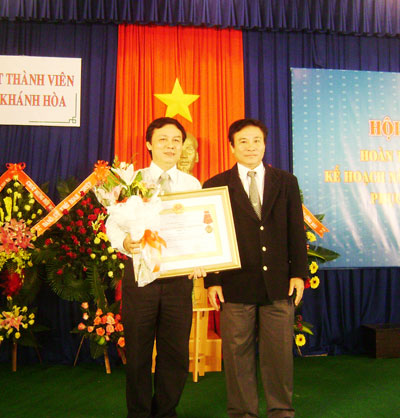 Thừa ủy nhiệm của Chủ tịch Nước, ông Mai Hữu Thu (phải) - Ủy viên Thường trực HĐND tỉnh, Phó Giám đốc Sở Nội vụ trao Huân chương Lao Động của Chủ tịch Nước cho ông Hoàng Aân.