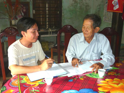 Ông Trịnh Dậu (phải) trao đổi công việc với cán bộ tư pháp xã tại nhà riêng.