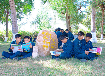  Chiến sĩ Sư đoàn Phòng không 377 đọc sách báo sau giờ huấn luyện trên thao trường.