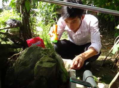 Cán bộ y tế dự phòng kiểm tra ấu trùng tại ổ dịch tổ 1 thị trấn Khánh Vĩnh.