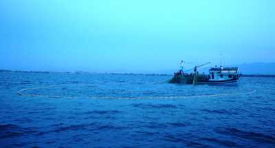 Một chiếc tàu đánh bắt thủy sản bằng chất nổ đang quay lưới trủ để đưa cá lên tàu.