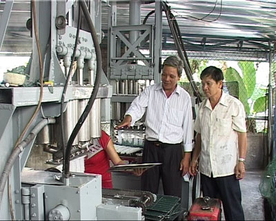 Ông Bùi Tiến Hòa (bên trái) và ông Huỳnh Văn Hiệp trước hệ thống sản xuất bánh hỏi tự động.