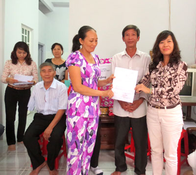 Bà Huỳnh Thị Phượng - Phó Chủ tịch Hội Liên hiệp Phụ nữ tỉnh (bìa phải) trao quyết định bàn giao nhà cho gia đình chị Phí.