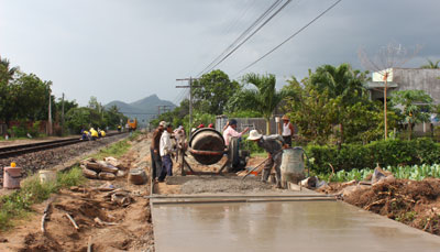 Các công nhân đổ bê tông cho đoạn đường gom tại thị trấn Vạn Giã.