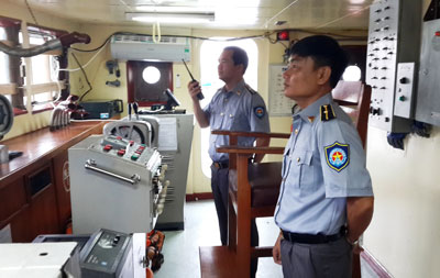 Thuyền trưởng Lê Minh Phúc (cầm bộ đàm) và kiểm ngư viên Trần Văn Huy trên ca bin điều khiển tàu KN 22 trở lại Hoàng Sa sau khi tàu được sửa chữa xong.
