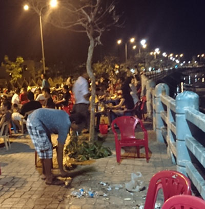 Nhân viên quán nhậu Sa Pin quét rác xuống sông.