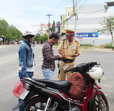 Cảnh sát giao thông kiểm tra giấy tờ xe người vi phạm an toàn giao thông.