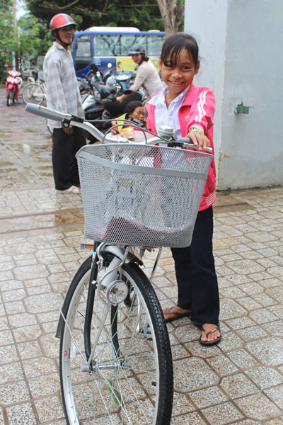 Em Cao Thị Tuệ, học sinh lớp 5, trường tiểu học Khánh Đông, vui mừng khi được tặng xe đạp để đi học. Trước đây, em phải đi bộ hơn 4km từ nhà đến trường mỗi ngày.