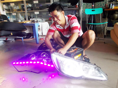 Nhân viên kỹ thuật kiểm tra đèn LED được lắp thêm vào đèn xe hơi.