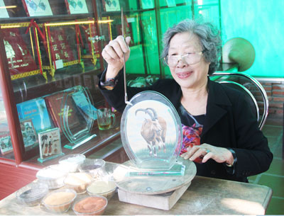 Nghệ nhân Trần Thị Thu đang hoàn thiện những nét cuối cùng của một bức tranh dê.