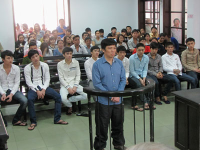 Bị cáo Nguyễn Hữu Hạnh (đứng) và 9 bị cáo (ngồi hàng ghế đầu).