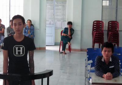 Bị cáo Trí (đứng) và Tấn Anh (bìa phải, ngồi).