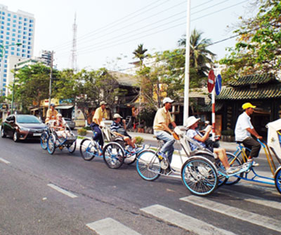 Du khách nước ngoài đi dạo phố bằng xe xích lô.