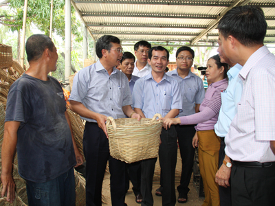Thứ trưởng Hoàng Quốc Việt (thứ 2 từ trái sang) đến thăm cơ sở đan cần xé của gia đình bà Trần Thị Thủy, nơi giải quyết việc làm cho hàng trăm lao động địa phương lúc nông nhàn.
