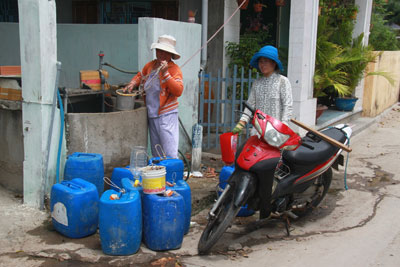 Người dân chắt từng gàu nước ở giếng công cộng. 