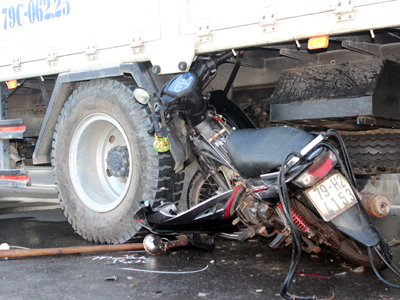 Chiếc xe máy bị cuốn vào bánh xe tải.