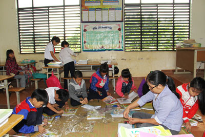 Giáo viên và học sinh Trường tiểu học Sơn Lâm (Khánh Sơn) đang bọc sách vở chuẩn bị năm học mới. Ảnh N.T