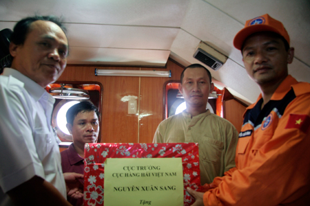 Ông Nguyễn Xuân Bình (bìa phải) trao quà của Cục trưởng Cục hàng hải Việt Nam cho thuyền trưởng Nguyễn Ngọc Hưng (thứ 2 từ trái qua).