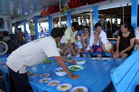 Nhân viên phục vụ trên một tàu du lịch chuẩn bị bữa ăn trưa cho khách.