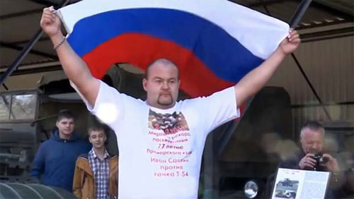 Savkin cầm cờ Nga sau khi kéo xe tăng. Ảnh: Uk.whaatsnew.com