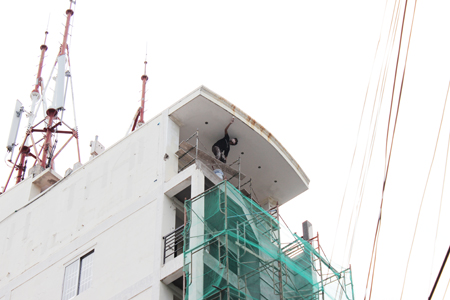 Một công nhân đứng trên giàn giáo mà không có dây đai an toàn