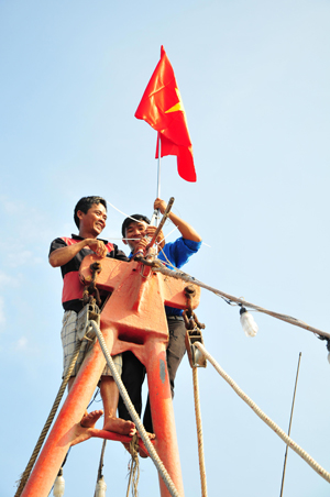 Các đoàn viên, thanh niên hỗ trợ ngư dân treo cờ.