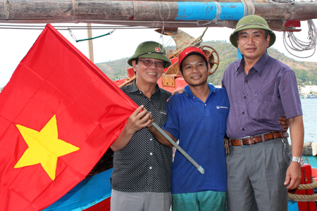 Đại diện Liên đoàn Lao động tỉnh Khánh Hòa và Báo Người Lao Động trao cờ Tổ quốc cho ngư dân.