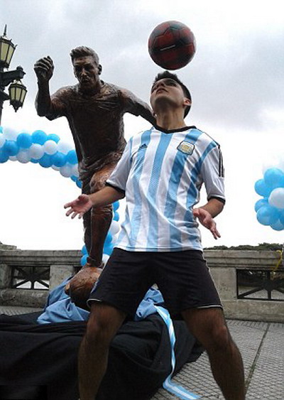 Một cầu thủ trẻ tâng bóng dưới tượng Messi.