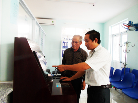 Công chức huyện Khánh Vĩnh hướng dẫn người dân tra cứu tiến độ giải quyết thủ tục hành chính trên máy tính