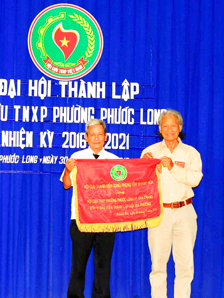 Ông Trương Hữu Hạnh (bên phải) - Chủ tịch Hội Cựu thanh niên xung phong tỉnh trao bức trướng cho Hội Cựu thanh niên xung phong phường Phước Long