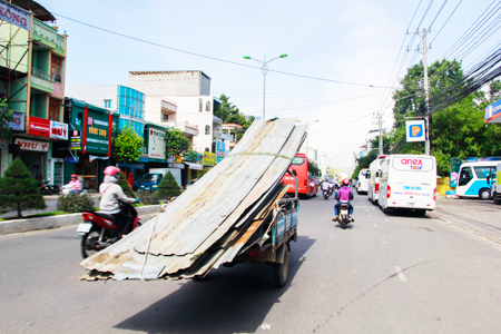 Một xe ba gác chở vật liệu lưu thông trên đường 23-10