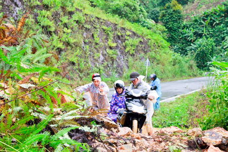 Người đi đường bằng xe máy cùng nhau đưa xe qua khu vực sạt lở