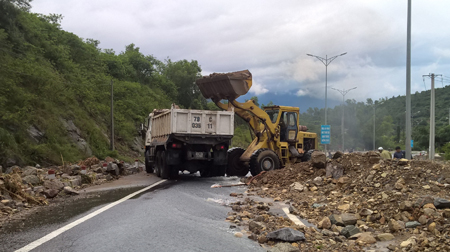 Công ty Cổ phần quản lý và xây dựng đường bộ Khánh Hòa huy động phương tiện dọn hàng chục mét khối đất đá bị sạt lở xuống đường 2-4.