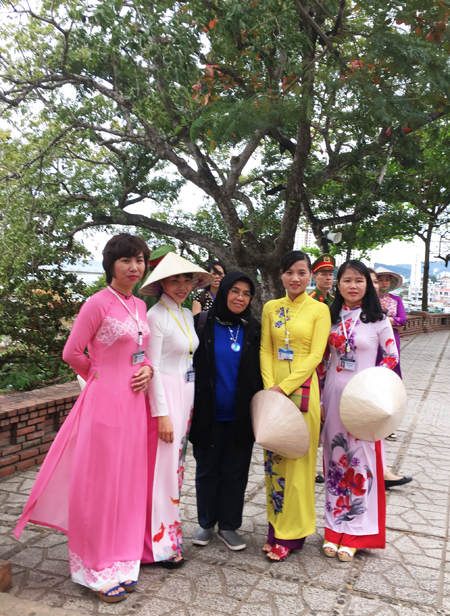 Delegates taking souvenir photo with tour guides wearing ao dai (Vietnamese traditional costume).