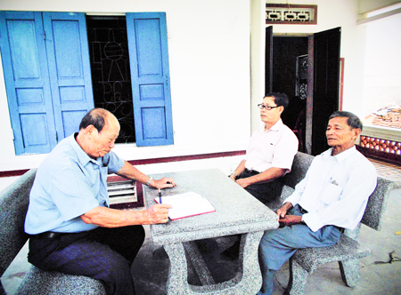 Ông Trần Công Tự (bên trái) trao đổi công việc trong thôn