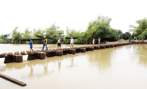 Người dân xã Vạn Long (huyện Vạn Ninh) tháo các ván chắn đập dâng Hải Triều trên sông Tô Giang để khơi thông dòng chảy trong đợt mưa lũ cuối năm 2016
