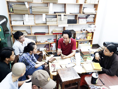 Anh Nguyễn Đức Khuynh hướng dẫn nhân viên thư viện Tu viện Huệ Quang phục chế và đóng bìa cho các sách đã hư cũ